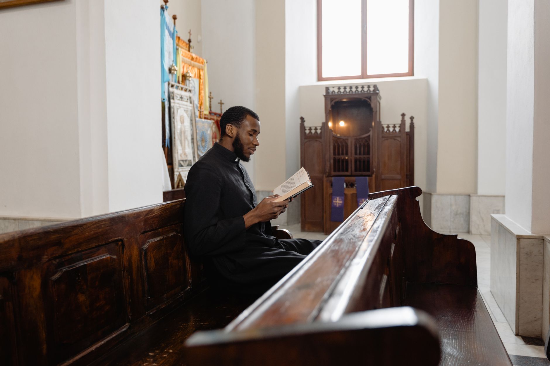 a priest in black vestment reading a bible